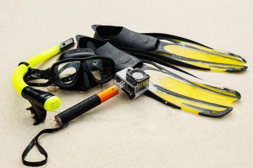 Equipment for snorkeling and action camera in waterproof case on the beach